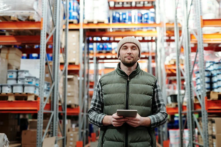 A photograph of a man standing in a warehouse.
