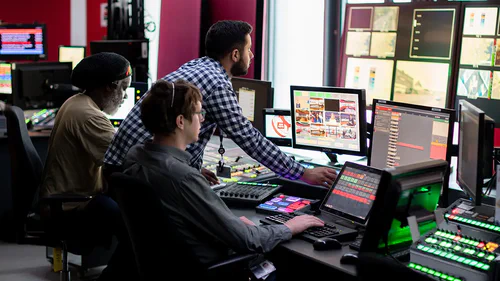 Photo of people looking at multiple computer screens.