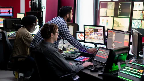 Photo of people looking at multiple computer screens.