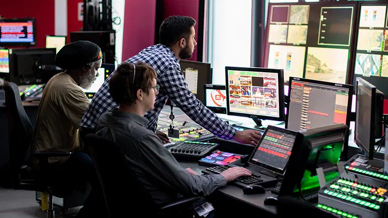 Photo of technology team looking at multiple monitors Photo of technology team looking at multiple monitors