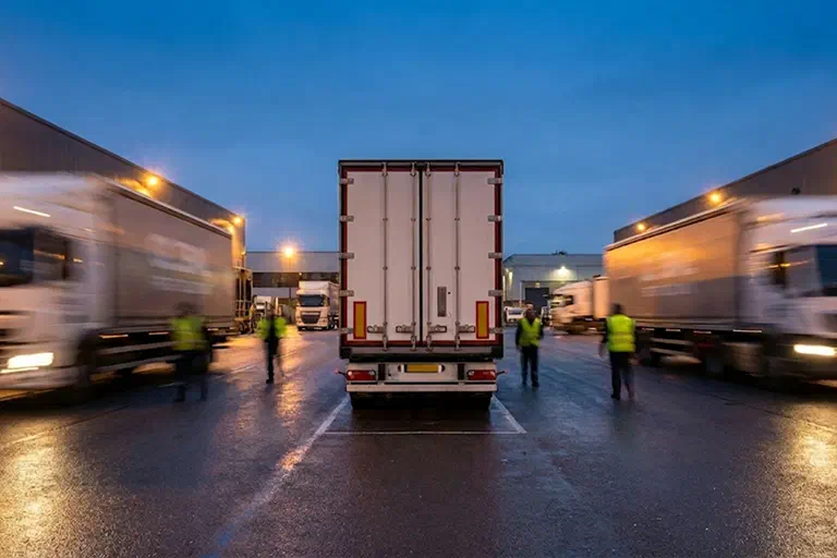 A photo of the back of a dry van at a warehouse. People are in motion beside it. A photo of the back of a dry van at a warehouse. People are in motion beside it.