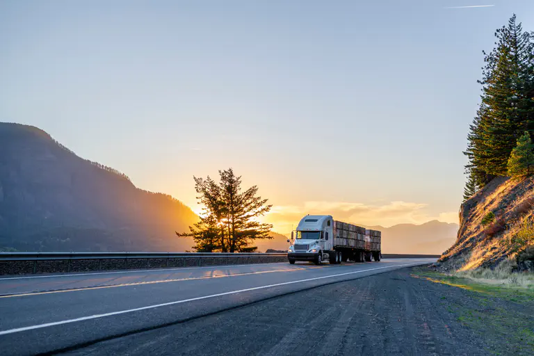 A photo of a semi truck driving down the highway.  
