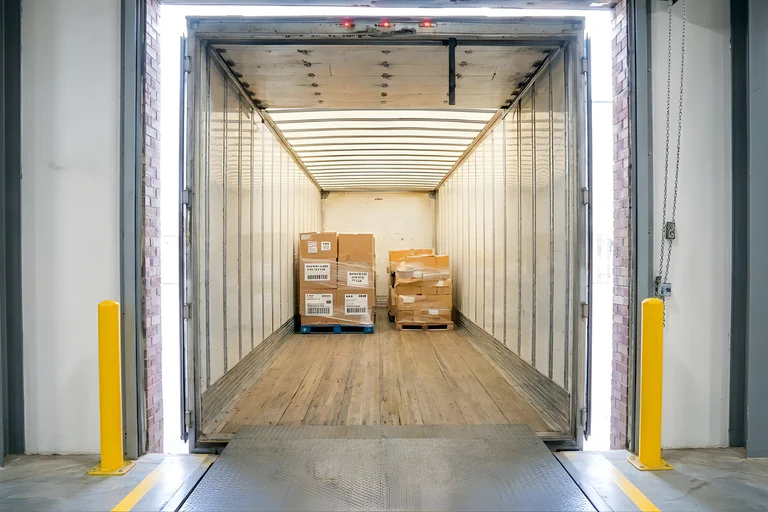 A photograph of a forklift unloading a semi truck trailer.