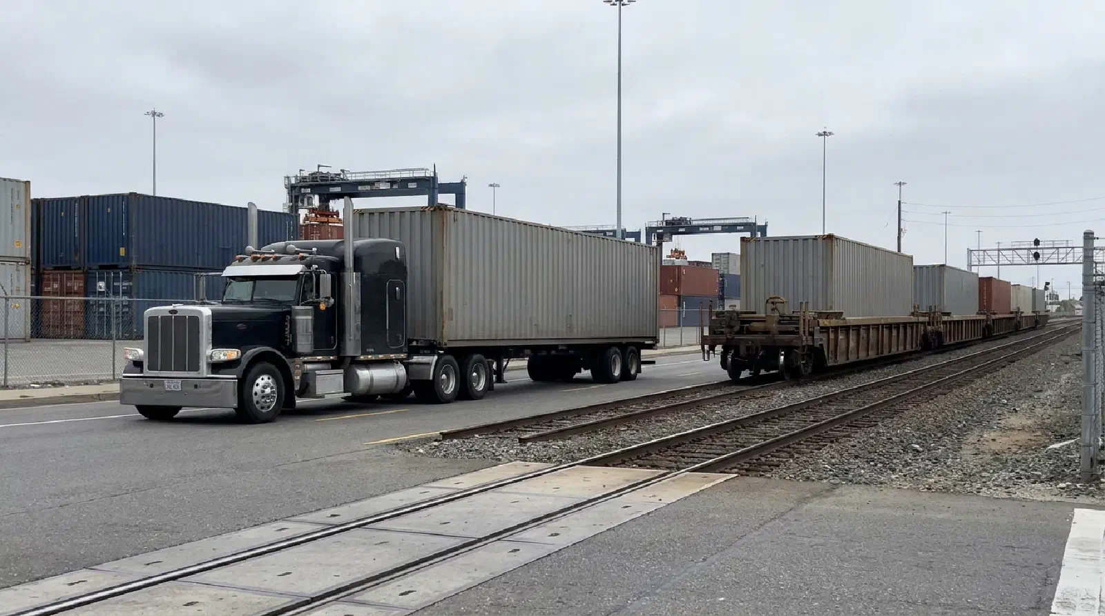 Intermodal container truck driving beside rail cars at a freight terminal. Intermodal container truck driving beside rail cars at a freight terminal.